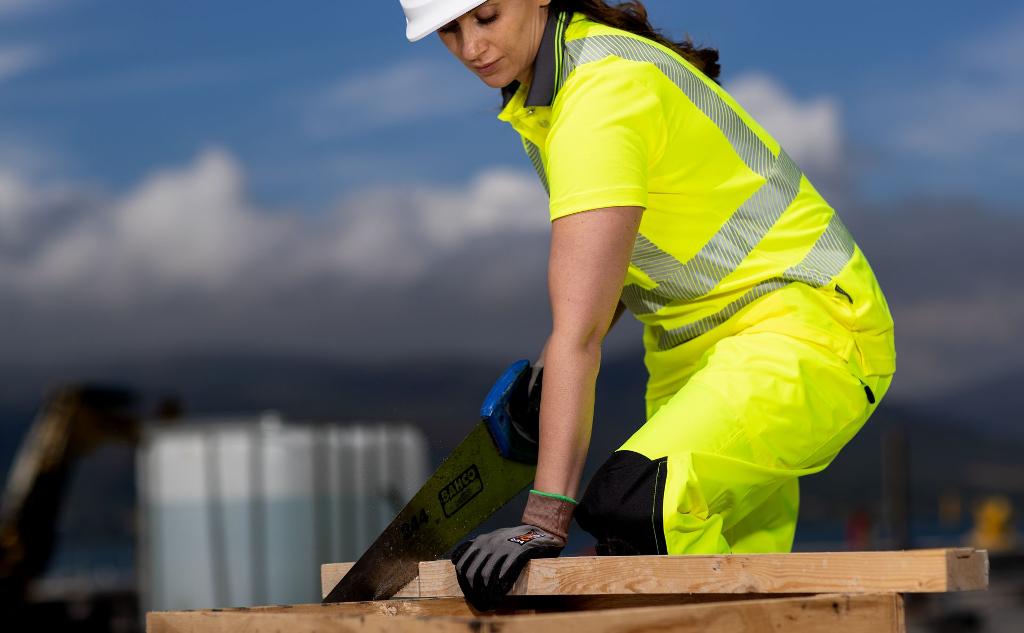 lady sawing wood in safety uniform