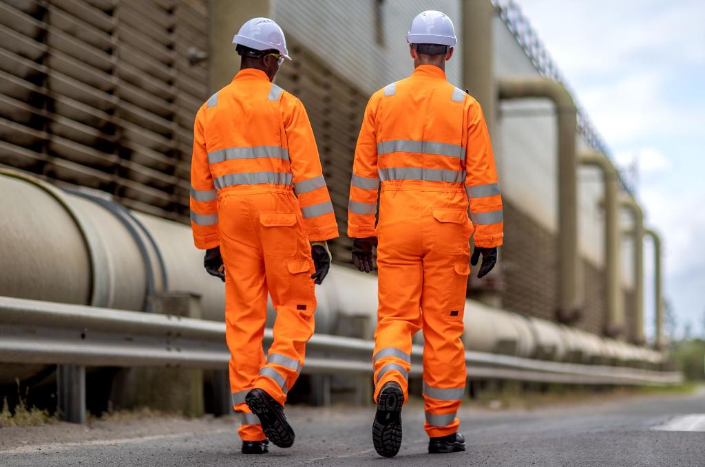 two men walking away in high vis orange coverall uniforms
