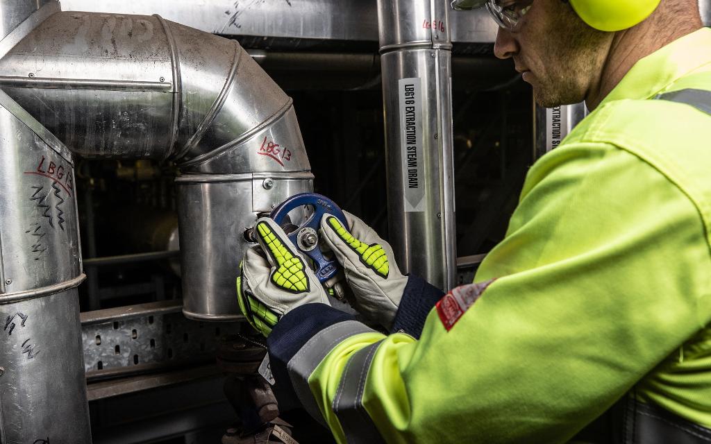 man turning valves in high vis gloves uniform