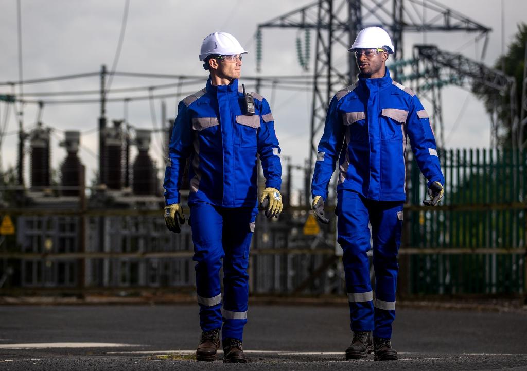 two men walking in hard hats safety wear and blue high visibility
