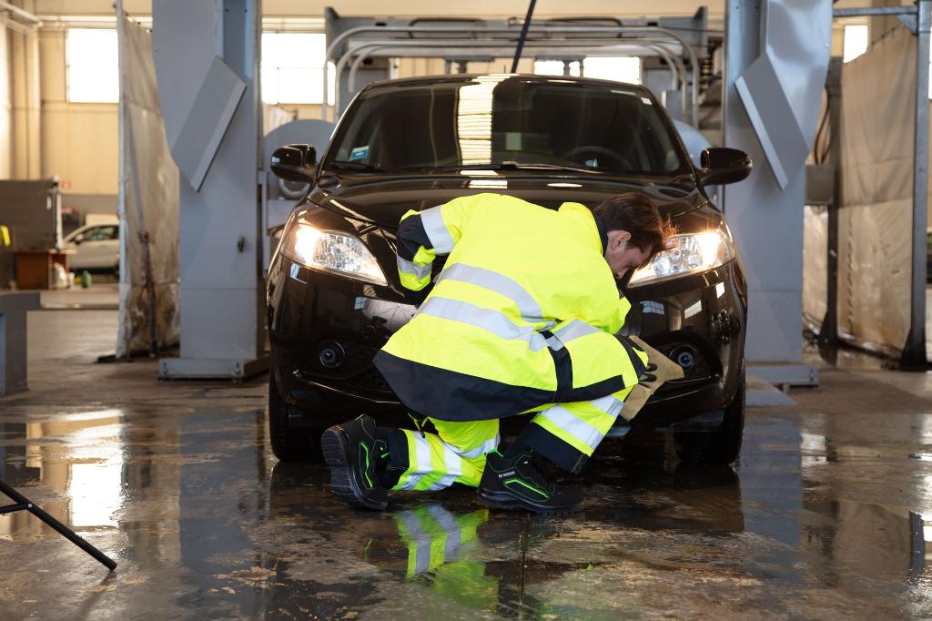 man cleaning car in yellow high vis workwear at car wash