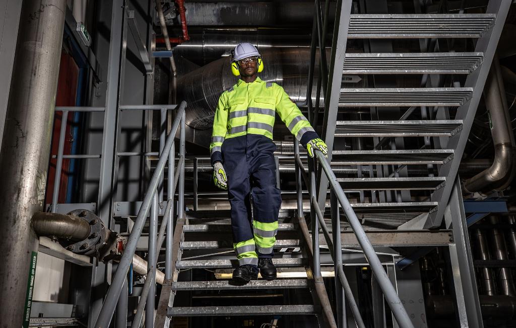 man walking down stairs in industrial environment wearing high vis and safety gear